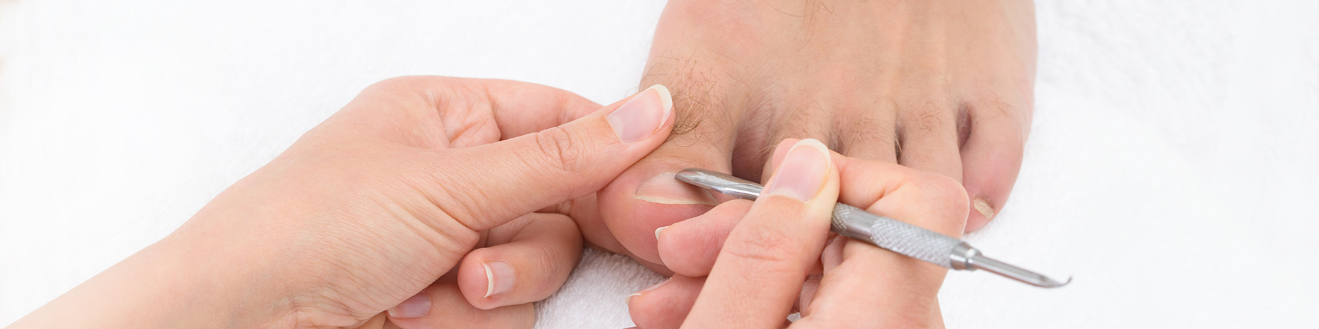 Fußpflege für Männer. Frauenhand mit Instrument entfernt an einem Männerfuß überschüssige Haut